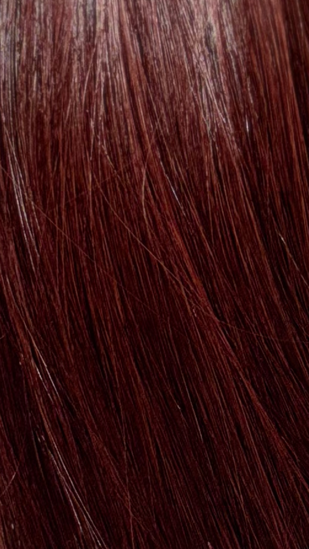 A close-up texture shot of straight, glossy dark auburn hair showing fine strands and subtle highlights.